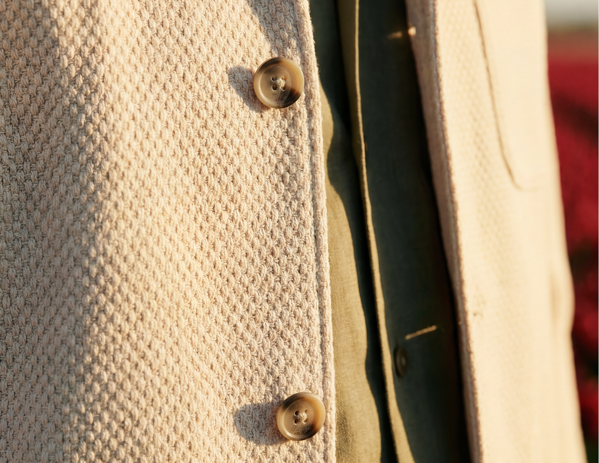 Close-up of a textured beige coat with buttons on a blurred background