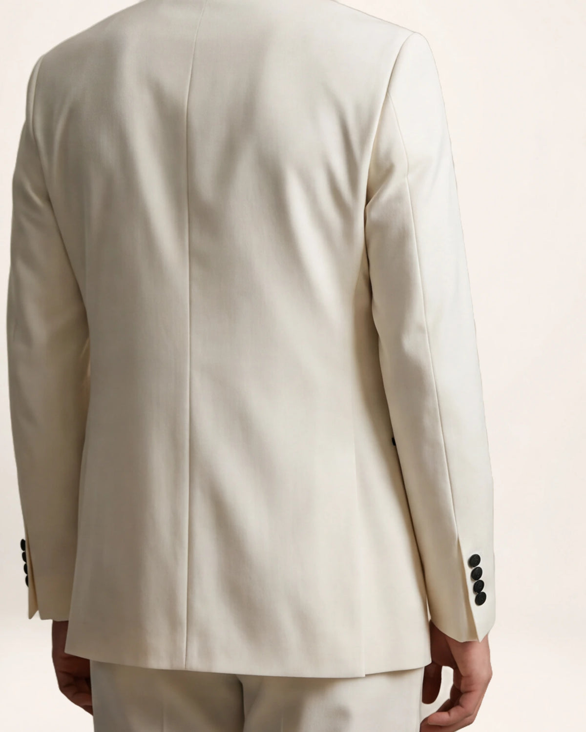 The Ascension Suit — ivory suit with black trim, back view on a model